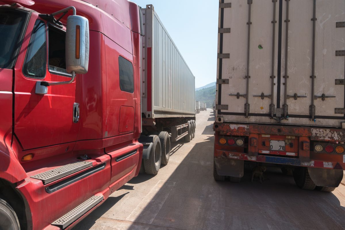 Heavy trucks loaded with goods trailers, parked in waiting area on state border crossing in Vietnam